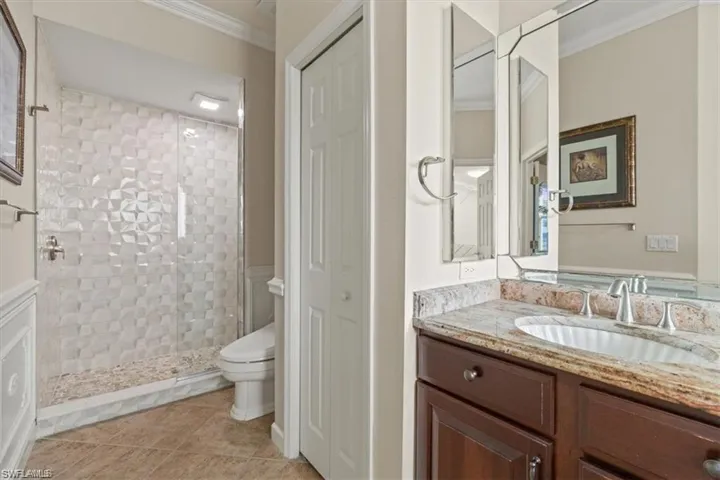 Bathroom featuring ornamental molding, toilet, a stall shower, vanity, and tile patterned flooring