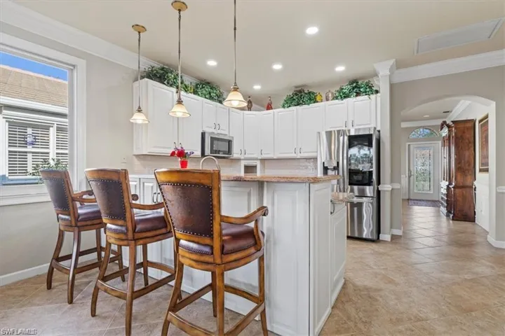 Kitchen featuring stainless steel appliances, arched walkways, crown molding, baseboards, and recessed lighting