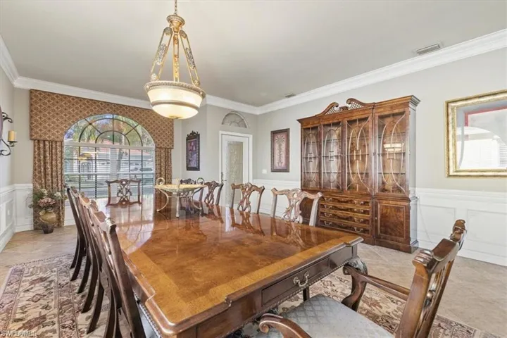 Dining space featuring a decorative wall, crown molding, and wainscoting