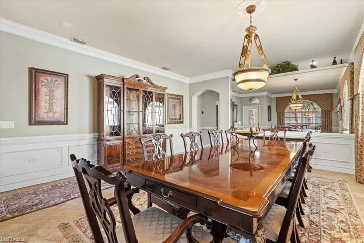 Dining space featuring crown molding, wainscoting, and arched walkways