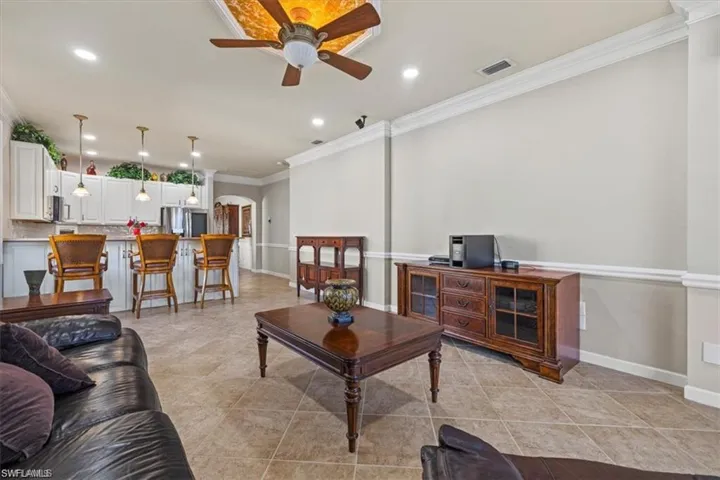 Living area with ornamental molding, ceiling fan, arched walkways, recessed lighting, and baseboards