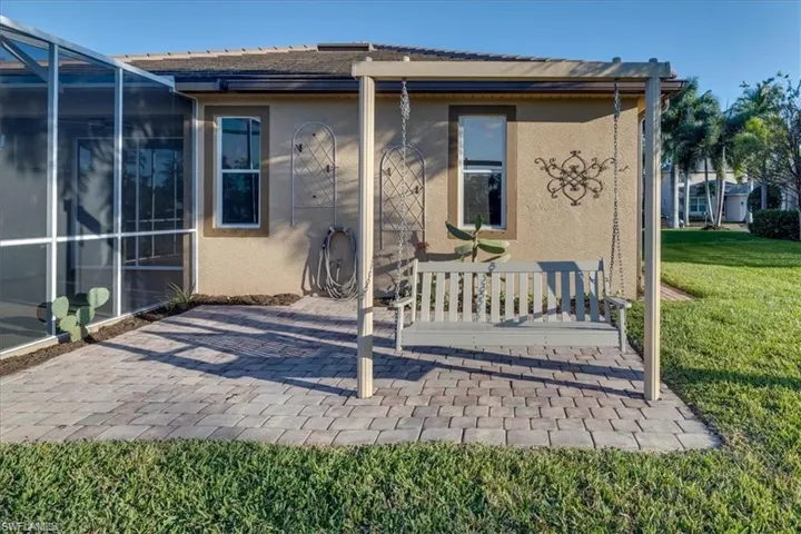 Rear view of house with stucco siding, a yard, a patio area, and a lanai