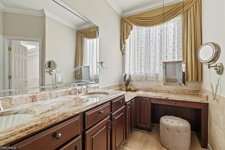 Full bathroom featuring crown molding, double vanity, and wood finished floors