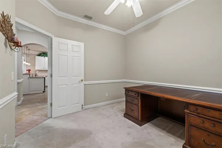 Unfurnished office with a ceiling fan, ornamental molding, a sink, arched walkways, and light colored carpet