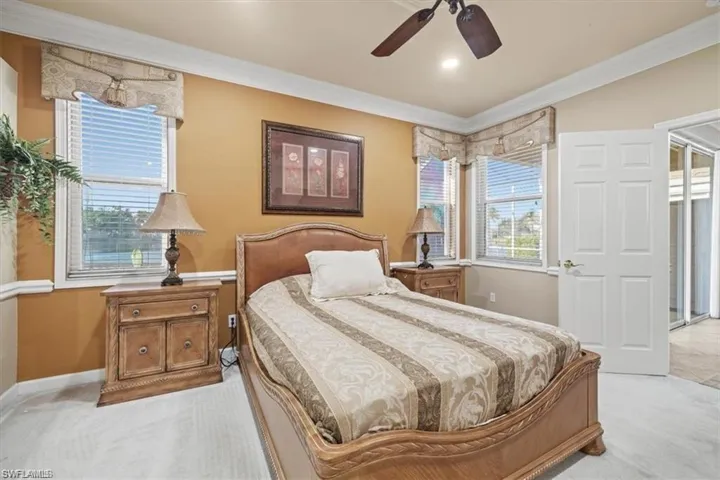 Carpeted bedroom featuring crown molding, a ceiling fan, and baseboards