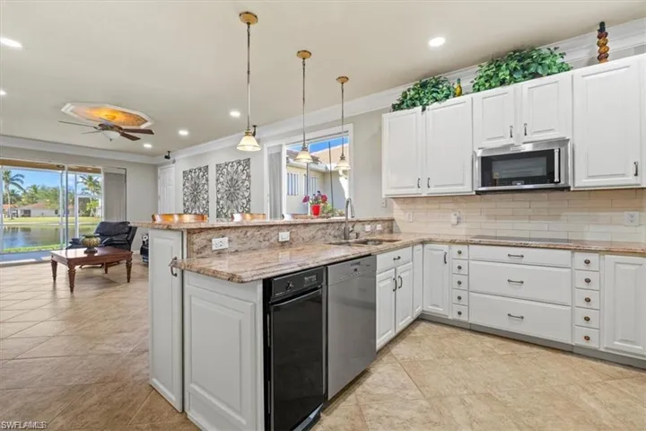 Kitchen featuring appliances with stainless steel finishes, a sink, ornamental molding, decorative backsplash, and a peninsula