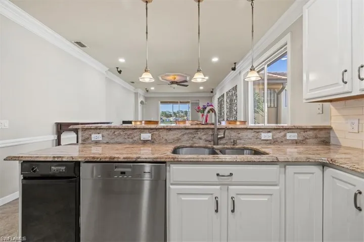 Kitchen with dishwasher, a sink, ornamental molding, tasteful backsplash, and white cabinets