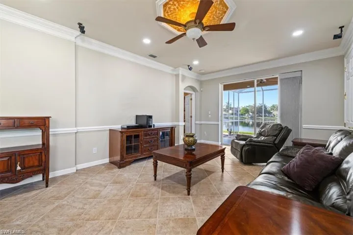 Living room with ornamental molding, a ceiling fan, arched walkways, recessed lighting, and a water view