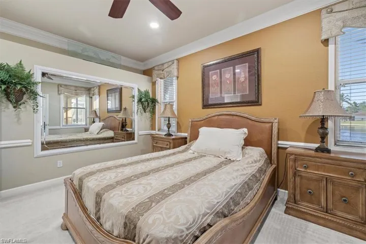 Bedroom featuring light carpet, ornamental molding, and ceiling fan