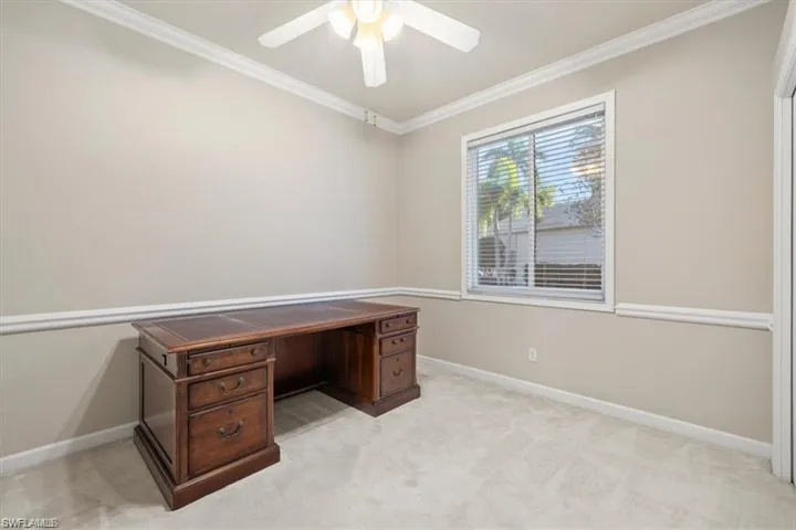 Unfurnished office with ornamental molding, baseboards, a ceiling fan, and light carpet
