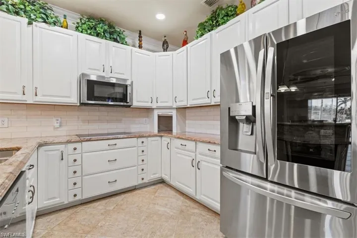 Kitchen featuring stainless steel appliances, white cabinets, recessed lighting, tasteful backsplash, and light stone countertops
