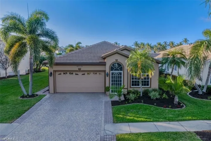 Ranch-style home with a garage, decorative driveway, a front yard, stucco siding, and a tiled roof