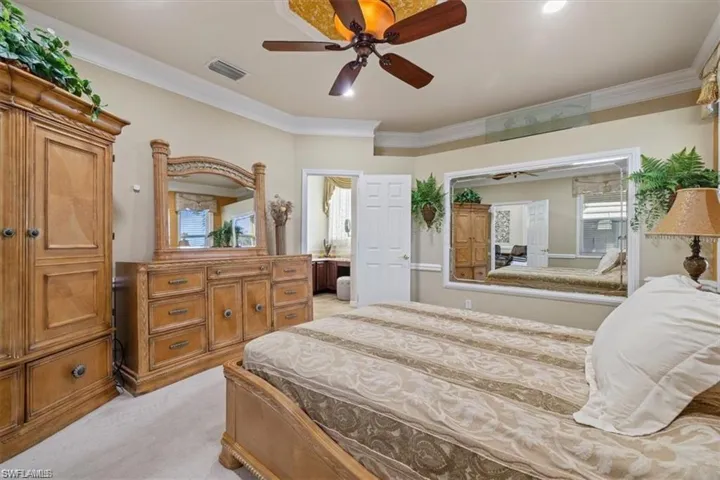 Bedroom featuring light carpet, ornamental molding, and ceiling fan