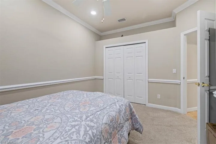 Bedroom with ornamental molding, carpet, a closet, baseboards, and ceiling fan