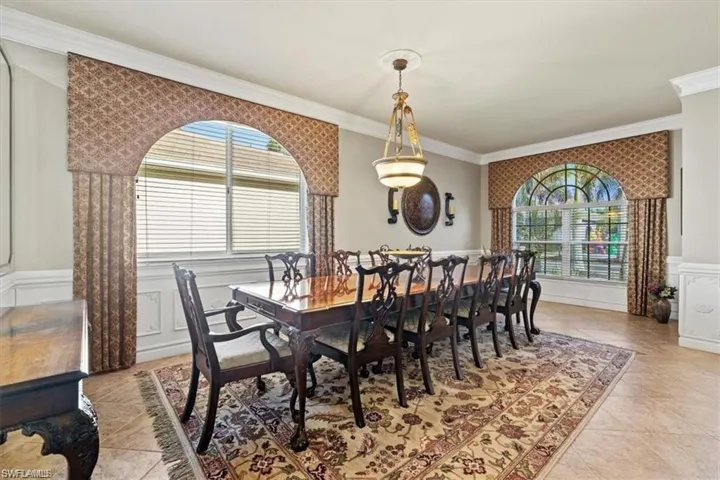 Dining space featuring ornamental molding, a decorative wall, a wainscoted wall, and light tile patterned floors