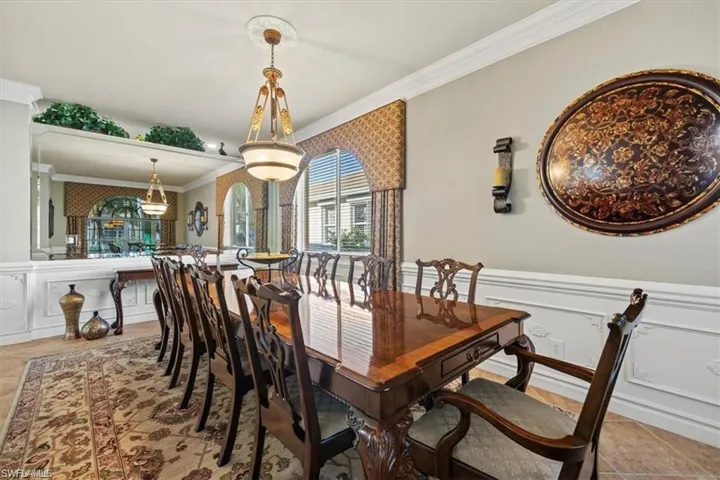 Tiled dining space featuring ornamental molding, a decorative wall, and a wainscoted wall