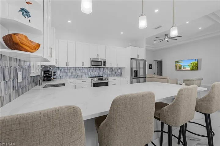 Another view of kitchen featuring white cabinetry, appliances with stainless steel finishes, sink, and decorative backsplash