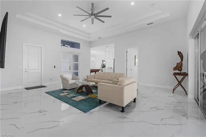 Living room with a high ceiling, ceiling fan, and a tray ceiling