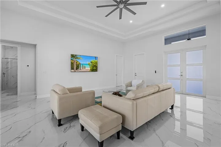 Living room featuring french doors, a ceiling fan, and a tray ceiling