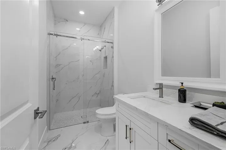 Bathroom featuring vanity, toilet, and a shower with shower door