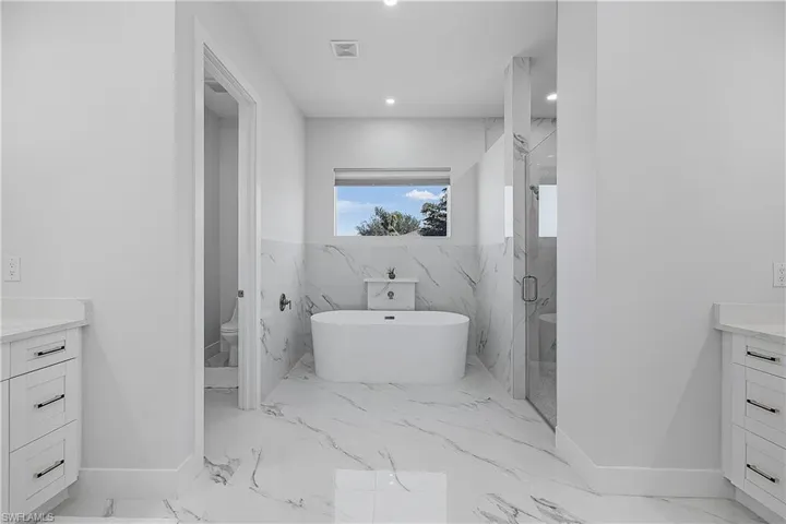 Full bathroom featuring vanity, separate shower and tub, and toilet