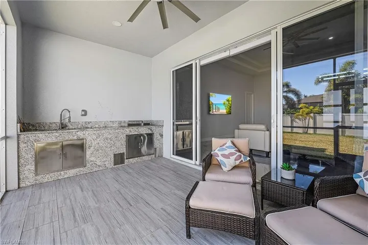 Covered lanai area featuring a ceiling fan and an outdoor kitchen