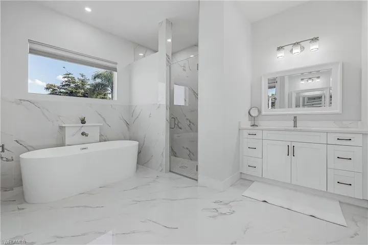 Bathroom featuring separate shower and bath and vanity