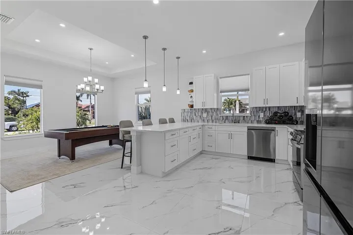 Kitchen featuring a raised ceiling, white cabinets, a kitchen breakfast bar, kitchen peninsula, and stainless steel appliances
