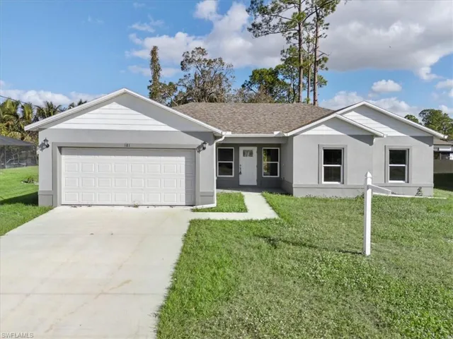 Ranch-style home featuring a garage and a front lawn