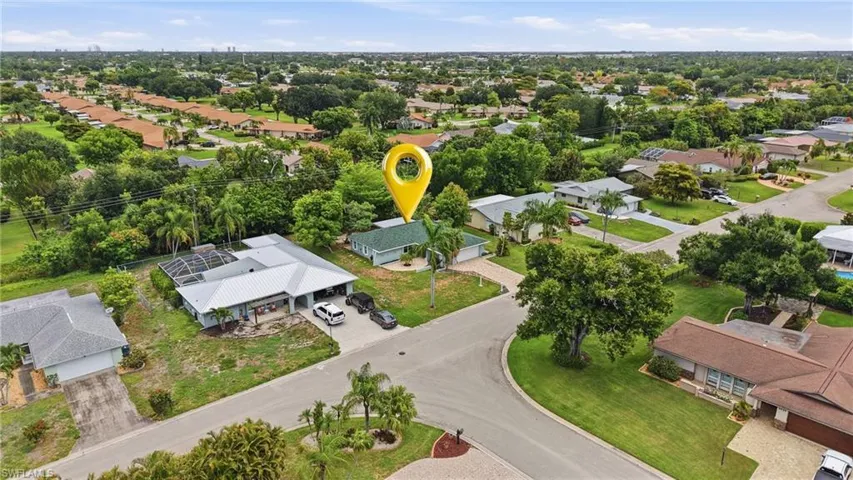 Aerial perspective showcasing a residential property with a light-colored roof and surrounding mature trees
