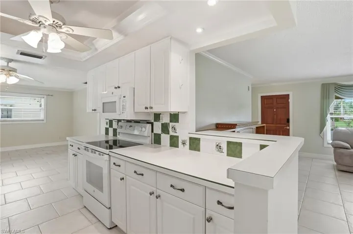 Spacious kitchen featuring abundant white cabinetry, white electric range, and matching microwave