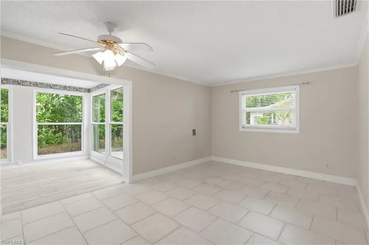 Bright interior space featuring a ceiling fan, crown molding, and neutral wall tones