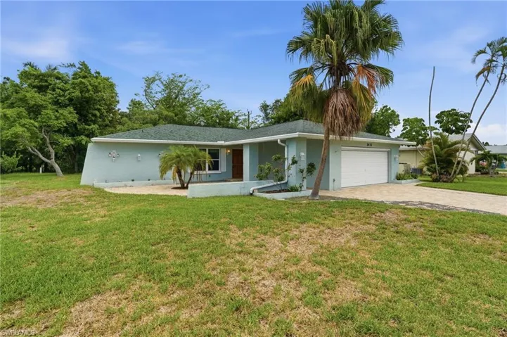 Single-story residence featuring light blue stucco exterior, a green shingle roof, white garage door, and a concrete driveway