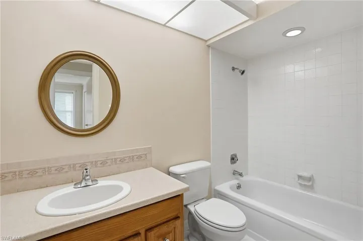 Bathroom featuring a single vanity with a solid surface countertop, white oval sink, and chrome faucet