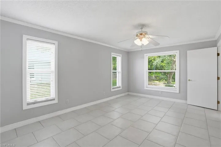 Spacious room featuring light gray walls, white trim, and rectangular tile flooring