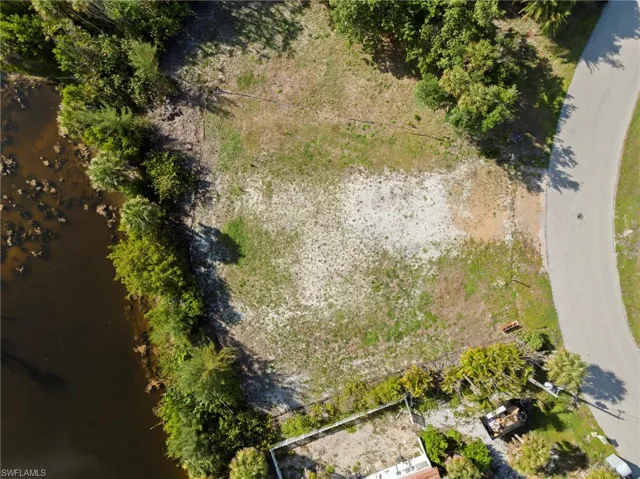 Expansive lot with a natural water feature, mature perimeter trees, and a paved road frontage