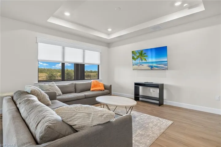 Living room with a tray ceiling and light wood-type flooring
