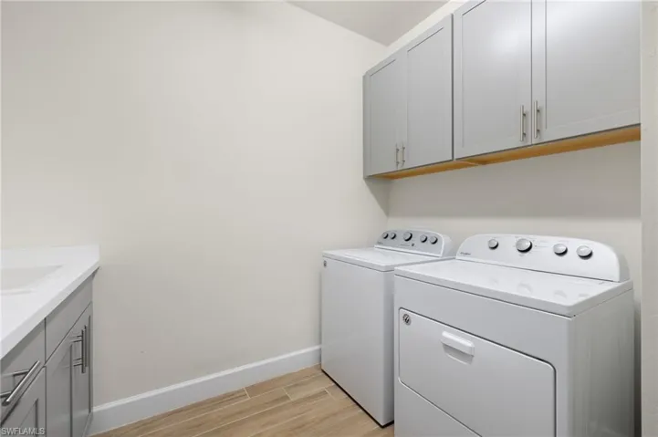 Washroom featuring washer and dryer, cabinets, and light wood-type flooring