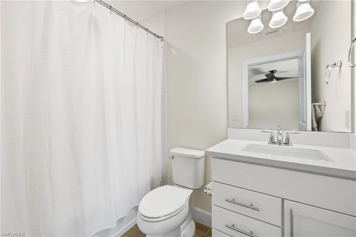 Bathroom with oversized vanity, toilet, and ceiling fan