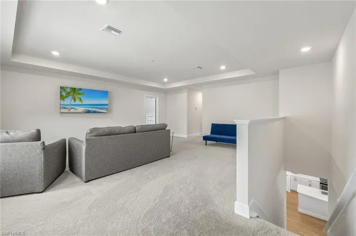 Living room featuring a raised ceiling and light wood-type flooring