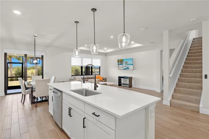 Kitchen with light hardwood / wood-style floors, a kitchen island with sink, stainless steel dishwasher, white cabinets, and sink