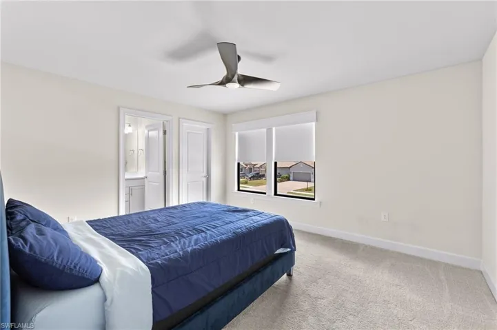 Carpeted bedroom featuring ensuite bathroom and ceiling fan