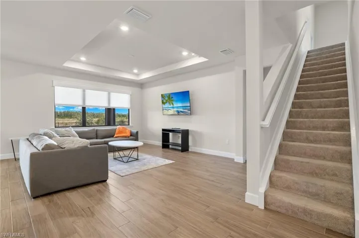 Living room with a raised ceiling and light hardwood / wood-style flooring