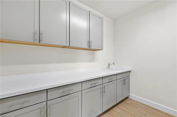 Clothes washing area with light hardwood / wood-style floors and sink
