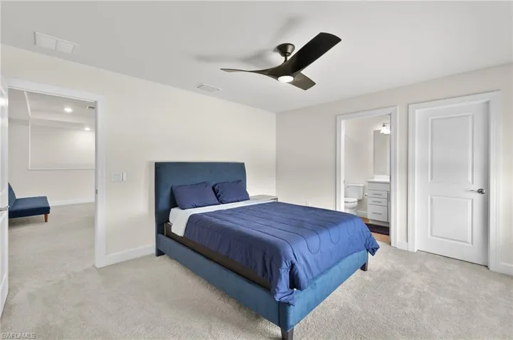 Bedroom featuring ceiling fan, ensuite bath, and light colored carpet