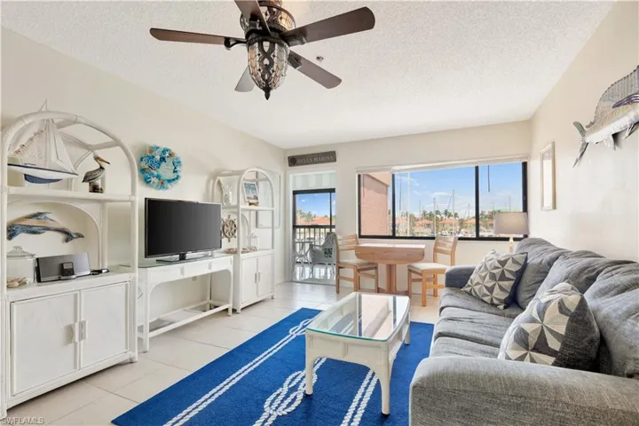 Living room featuring a textured ceiling, light tile patterned floors, plenty of natural light, and ceiling fan