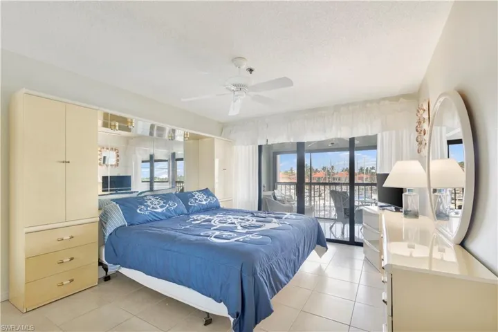 Bedroom featuring access to exterior, light tile patterned floors, a textured ceiling, and ceiling fan