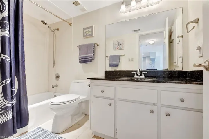 Bathroom featuring vanity, shower / bath combo with shower curtain, and tile patterned floors