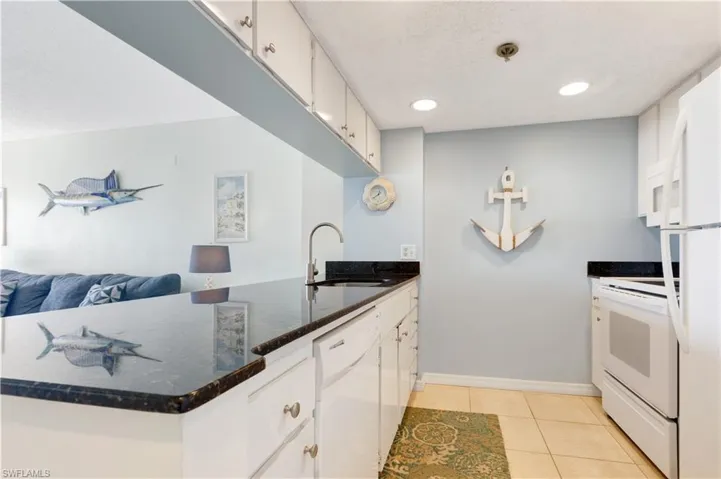 Kitchen with white appliances, a peninsula, white cabinetry, light tile patterned floors, and open floor plan