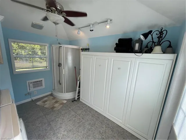 Full bath featuring lofted ceiling, a shower stall, track lighting, and a ceiling fan